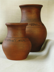 Two clay pots on the background of linen cloth with pleats close up