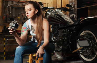 Fototapeta na wymiar Serious female biker keeping screwdriver in left hand