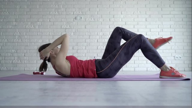 Young woman doing stomach exercise on mat on floor at home, 4K
