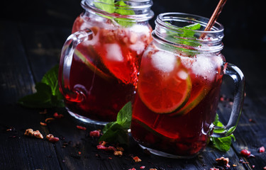 Frozen red tea with lime, ice and mint in glass jars, dark background, selective focus