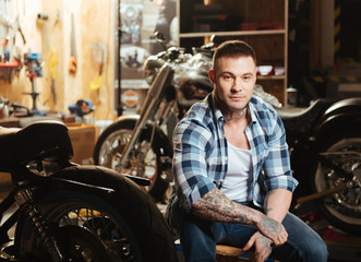 Attractive young man sitting between motorbikes