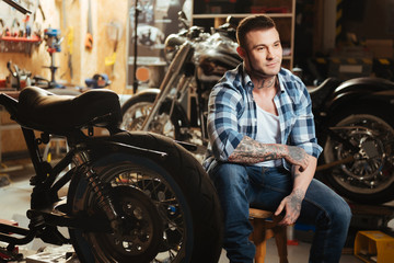 Happy smiling man sitting between motorcycles