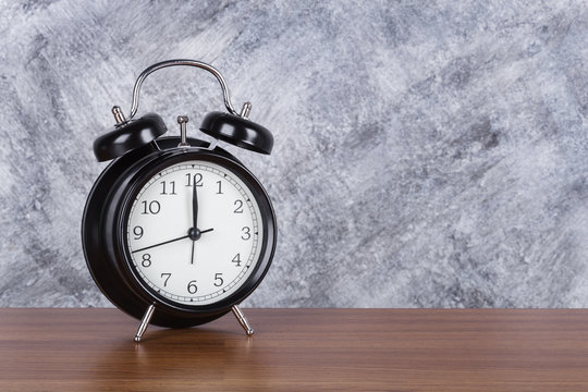 12 o'clock vintage clock on wood table and wall background