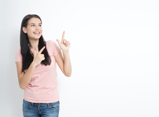 Look here. Attractive young woman pointing to space. Friendly smiling girl pointing at copyspace...