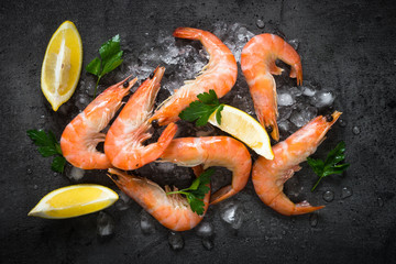 Fresh Prawns Shrimps with lemon on ice. Top view black slate table