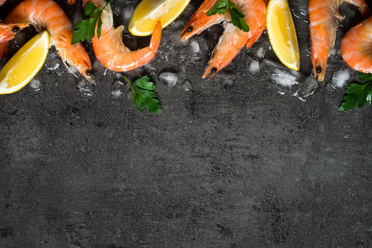Fresh Prawns Shrimps with lemon on ice. Top view black slate table