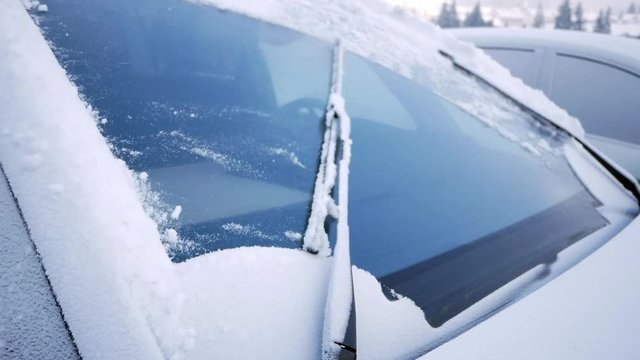 Close-up of windshield wipers brushing away snow from a car's windshield