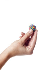 Hand holding a traditional candy from Brazil called brigadeiro over white background