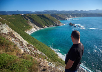Un hombre joven contemplando el paisaje en la costa de Asturias