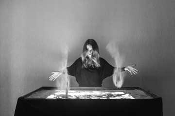 The woman draws on sand, sand animation, sand spilling out of two hands