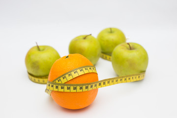 orange and green apple with a measuring tape on a white background