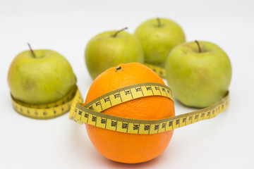 orange and green apple with a measuring tape on a white background