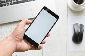Man using  mobile phone view of a laptop in high definition and coffee with on woodden white background