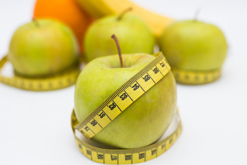 green apples and measuring tape banans orange on a white background. Healthy lifestyles concept