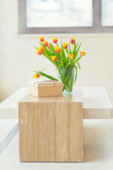 Beautiful bouquet of tulips in glass vase on table, ready to make a present with gift box for beloved person