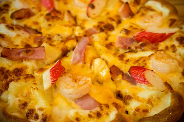 Pizza with a mixture of shrimp, crab, cheese, ham, pineapple.