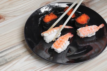 hand holding sushi chopsticks on a black plate wooden table  background