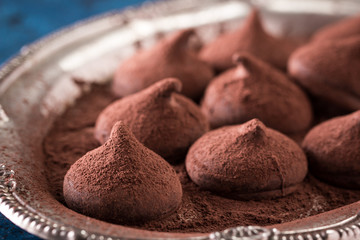 Assorted dark chocolate truffles with cocoa powder on dark blue table