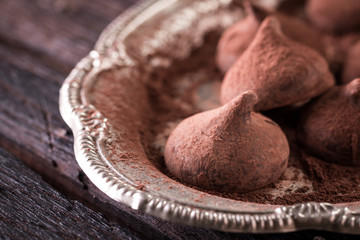 Assorted dark chocolate truffles with cocoa powder on dark blue table