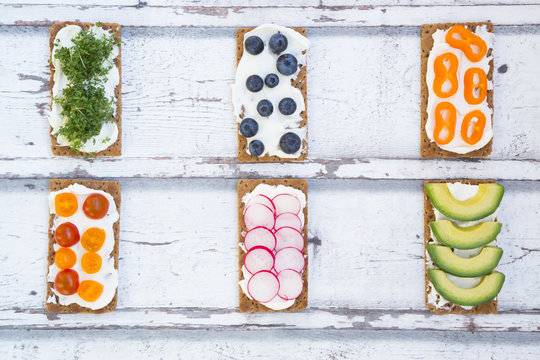 Crisp bread with cream cheese and avocado, radish, capsicum, cress, tomatoes and blueberries