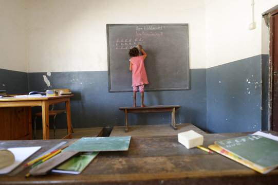 Madagascar, Fianarantsoa, Schoolgirl writing on blackboard
