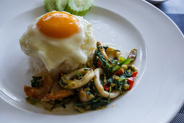 Rice and shrimp and squid and basil topped with Fried egg. Thai food style.