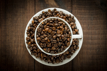 Coffee beans in the cup on dark wooden background