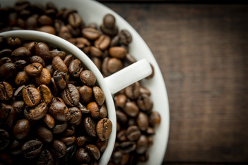 Coffee beans in the cup on dark wooden background