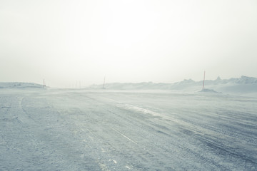 A beautiful landscape with a white, snowy road with safety poles in the Norwegian winter