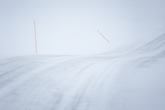 A beautiful landscape with a white, snowy road with safety poles in the Norwegian winter