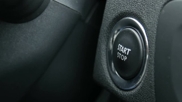 Macro footage of a female driver pressing an engine start and stop button of a car with the hand with a glove.