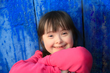 Young girl smiling on background of the blue wall.
