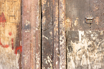 Old peeling wooden gate, bathed in red paint on a small street in Palermo. Italy.