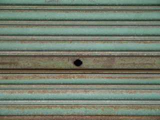 穴の開いた緑の古いシャッター