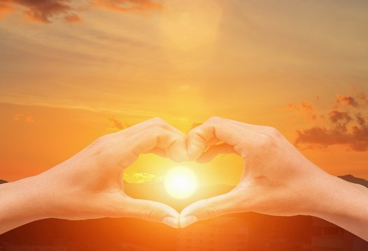 hand forming  a heart shape with  sunset  light and copy space for add text