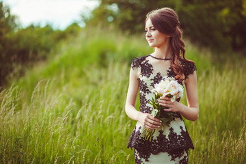 Beautiful young woman in dress with black laces holds bouquet of white peonies