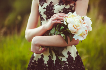 Tender white peonies lie on woman's arm