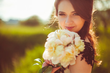 Sun makes halo around woman's face while she poses with bouquet of peonies