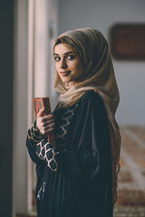 Beautiful Muslim girl standing next to a window