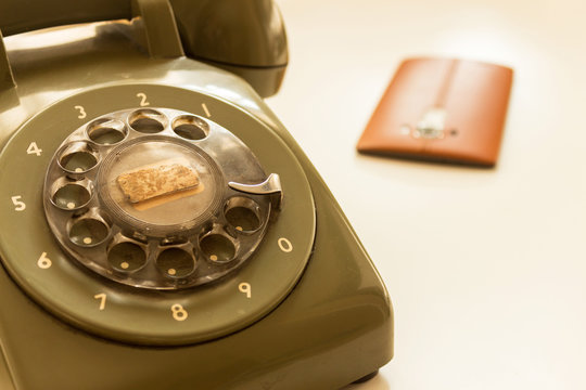 Green retro phone and snuff colored smart phone on white ground