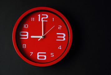 Modern red clock with black background.
