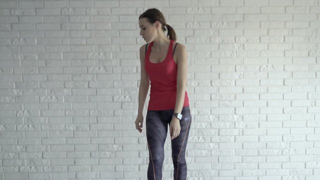Tired woman taking break and drinking after exercising crouch at home
