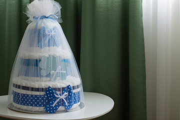 Big cake of diapers with blue bow, baby shower gift.