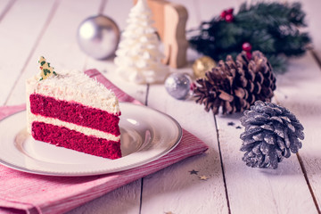 Christmas cake on plate on red fabric on wood background and decorations