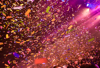 Confetti fired on air during a concert. People are happy and with hands in the air. Image ideal for backgrounds. Yellow, orange and pink are the tones of the picture
