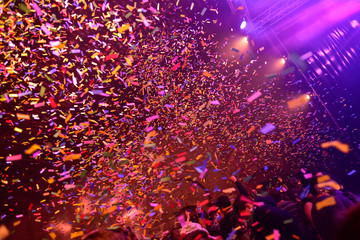 Confetti fired on air during a concert. People are happy and with hands in the air. Image ideal for...