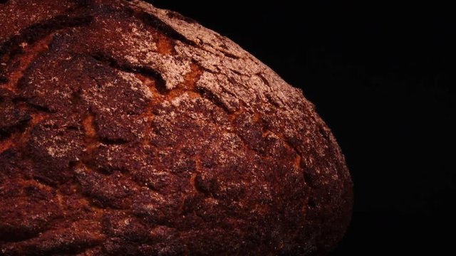 Fresh baked round bread rotating against black background. Close up view with blank space. Tasty pastry product for your breakfast in 4K Ultra HD 3840x2160
