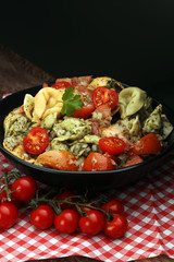 Bowl of tricolor tortellini pasta salad with tomatoes and onions