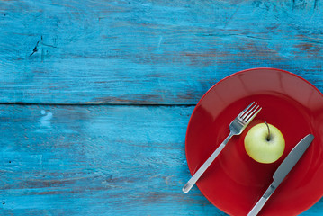 Diet. Green Apple on red plate with Cutlery