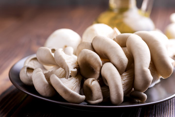 Fresh mushrooms on a wooden background Close up Bottle with olive oil